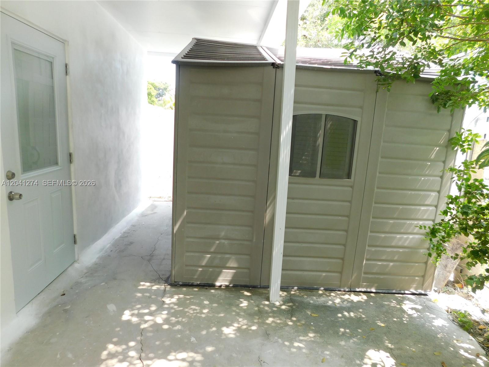 A beige plastic storage shed sits on a concrete patio next to a white door — 2230 NW 58th St # B, Miami FL 33142, MIAMI, FL