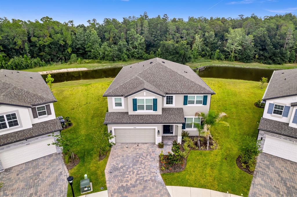 An aerial view shows a two-story suburban house with a paved driveway and a pond — 10742 NEW MORNING DRIVE, TAMPA, FL