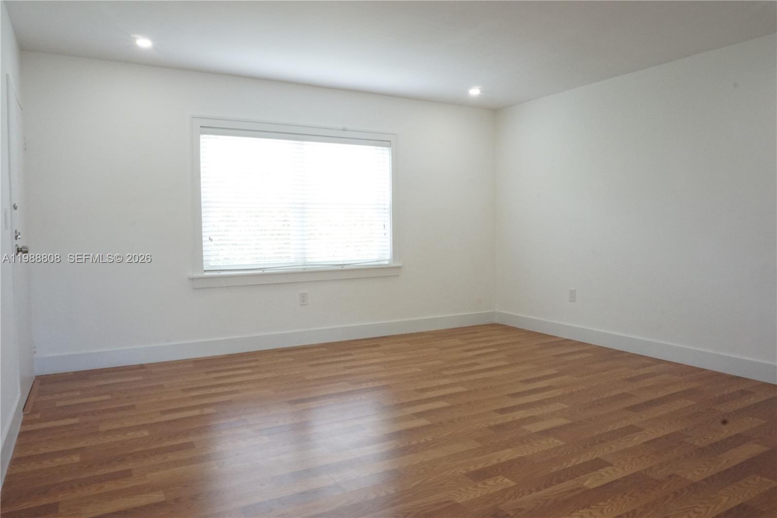 An empty room features white walls, wood-look flooring, recessed lighting, and a single window — 7701 SW 55th Ave # C, Miami FL 33143, MIAMI, FL