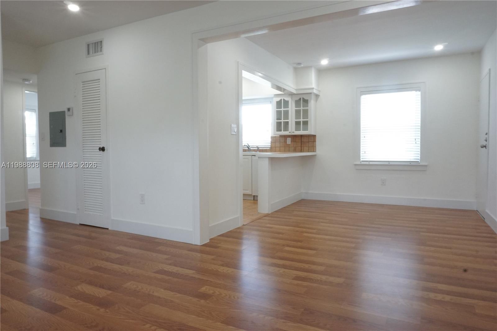 A living area with wood-look flooring leads into a kitchen with a breakfast bar — 7701 SW 55th Ave # C, Miami FL 33143, MIAMI, FL