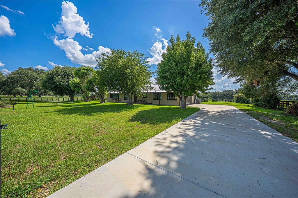 A concrete driveway leads to a single-story house surrounded by a large grassy yard — 15111 NW 34TH TERRACE, OKEECHOBEE, FL