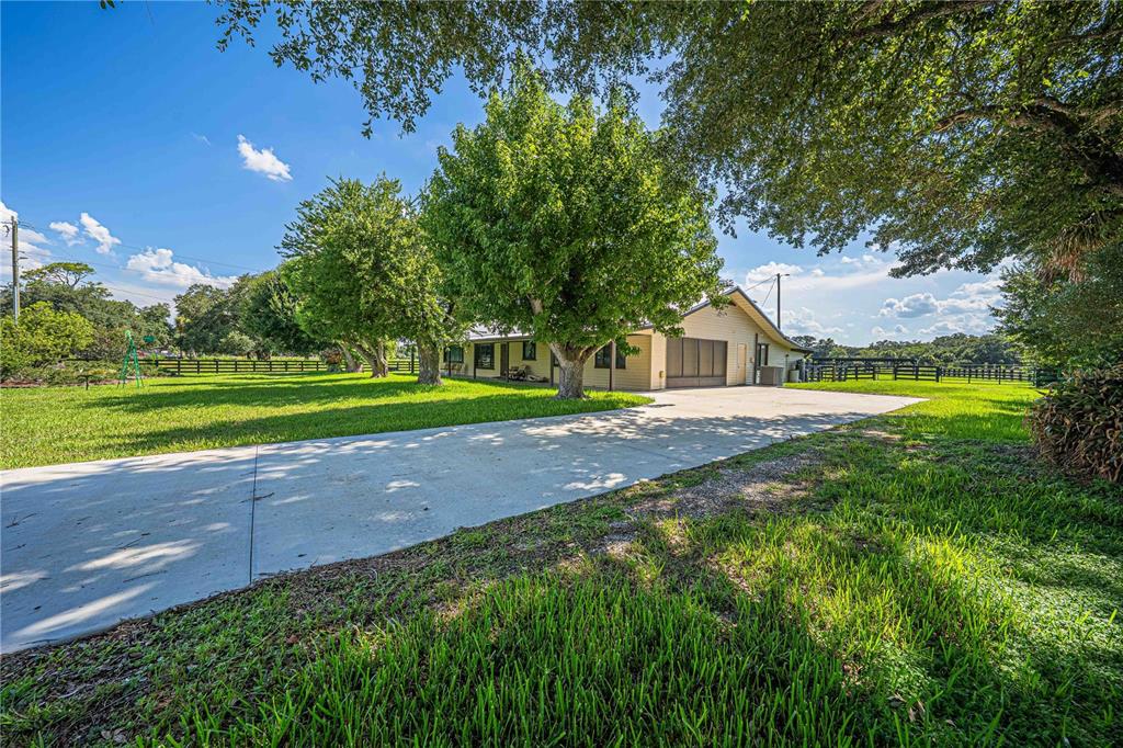 A concrete driveway leads to a single-story house with a garage and surrounding green lawn — 15111 NW 34TH TERRACE, OKEECHOBEE, FL