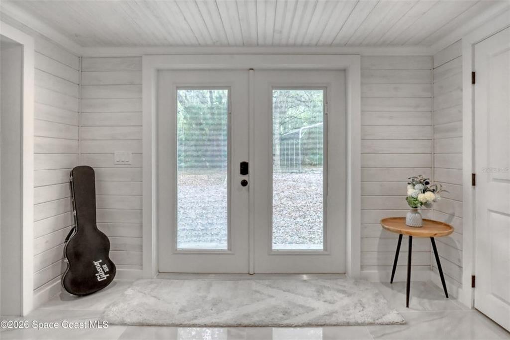 An entryway features white shiplap walls, a double glass door, and a guitar case — 4325 N HIGHWAY 1, MIMS, FL