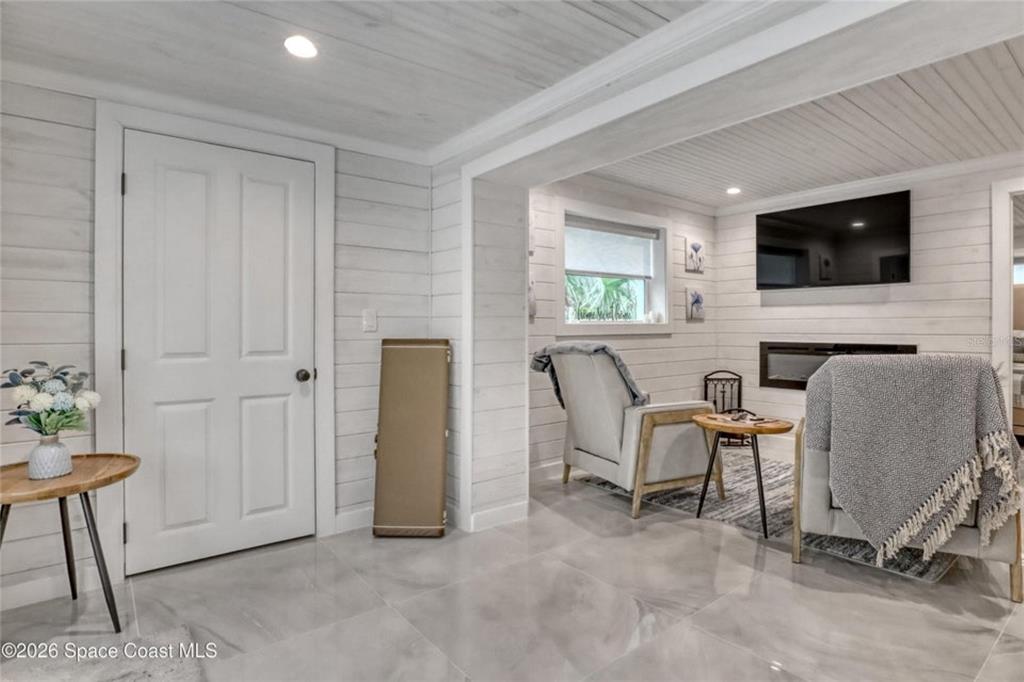 A living room features white shiplap walls, tile flooring, a fireplace, and two armchairs — 4325 N HIGHWAY 1, MIMS, FL