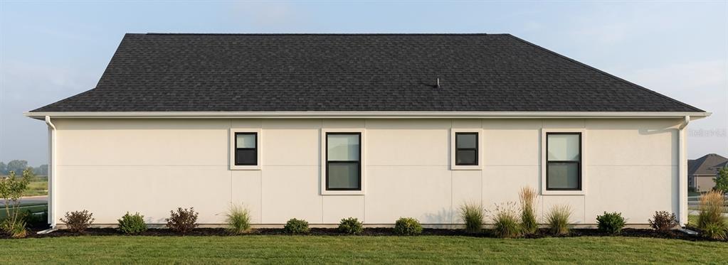 The exterior side view of a house features white stucco walls, black-framed windows, and a roof — 4800 16TH AVENUE S, ST PETERSBURG, FL