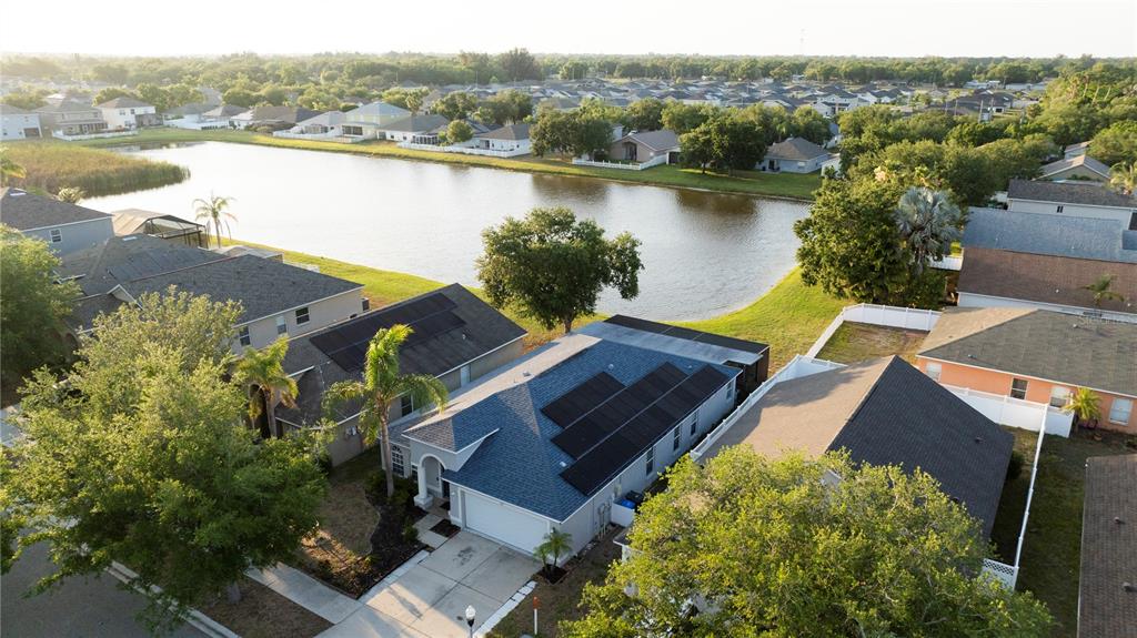 An aerial view shows suburban houses with solar panels near a lake — 210 SMOKEY HILL AVENUE, RUSKIN, FL