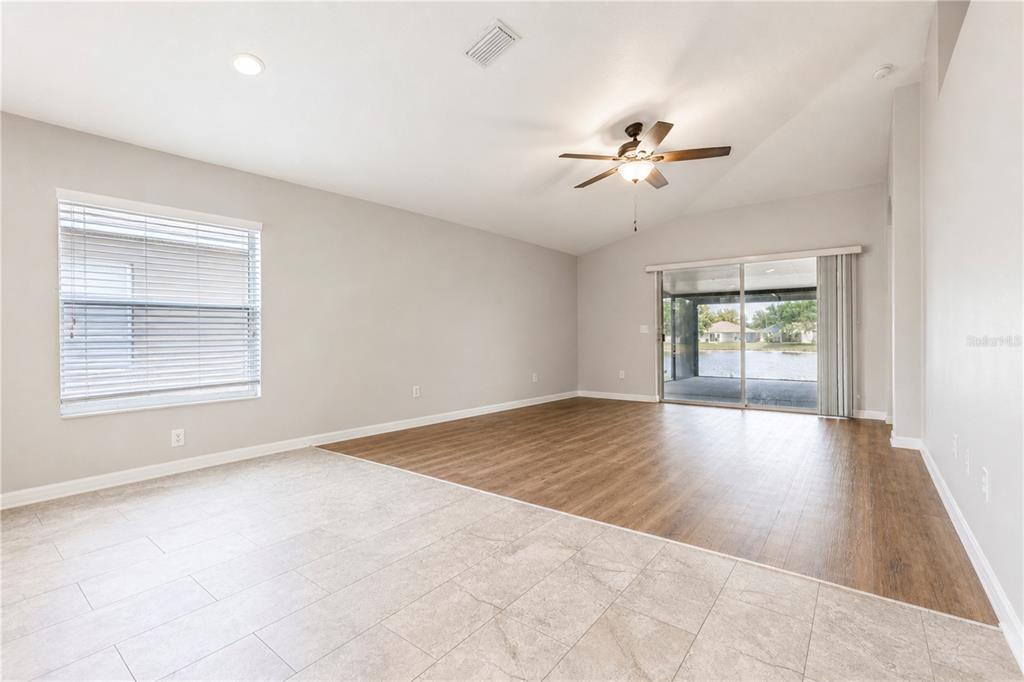 A living room features a combination of tile and wood-look flooring, a ceiling fan, and sliding doors — 210 SMOKEY HILL AVENUE, RUSKIN, FL