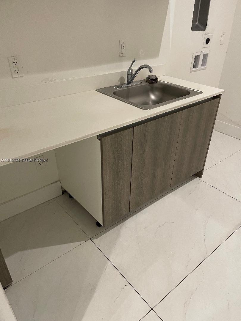 A laundry room features a stainless steel sink, white countertop, and wood-toned cabinets — 301 Altara Ave # 3J, Coral Gables FL 33146, CORAL GABLES, FL