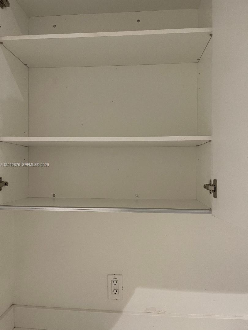 This image shows an open white cabinet with two shelves and an electrical outlet below — 301 Altara Ave # 3J, Coral Gables FL 33146, CORAL GABLES, FL