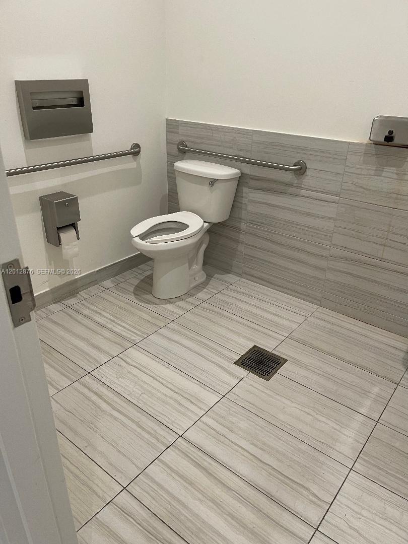 An accessible bathroom features a toilet, grab bars, and light-colored tile flooring and walls — 301 Altara Ave # 3J, Coral Gables FL 33146, CORAL GABLES, FL