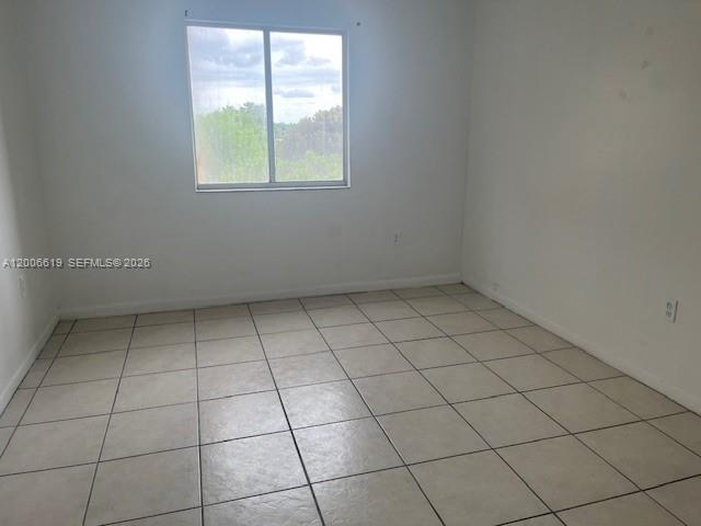 An empty bedroom features white walls, a single window, and light-colored tile flooring — 15231 SW 80th St # 503, Miami FL 33193, MIAMI, FL