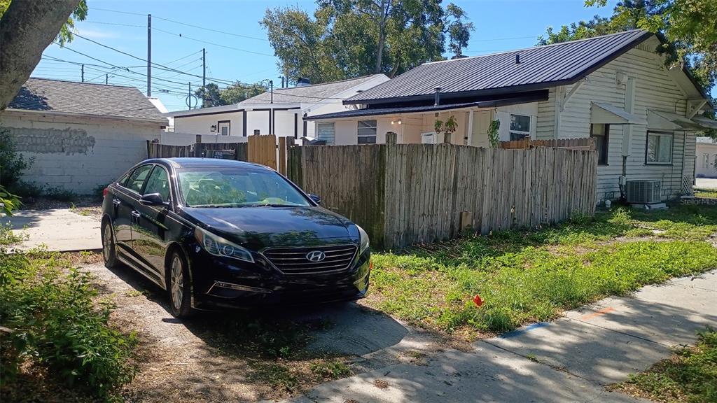 A black sedan is parked on a dirt driveway in front of a small house — 1623 7TH AVE N, ST PETERSBURG, FL