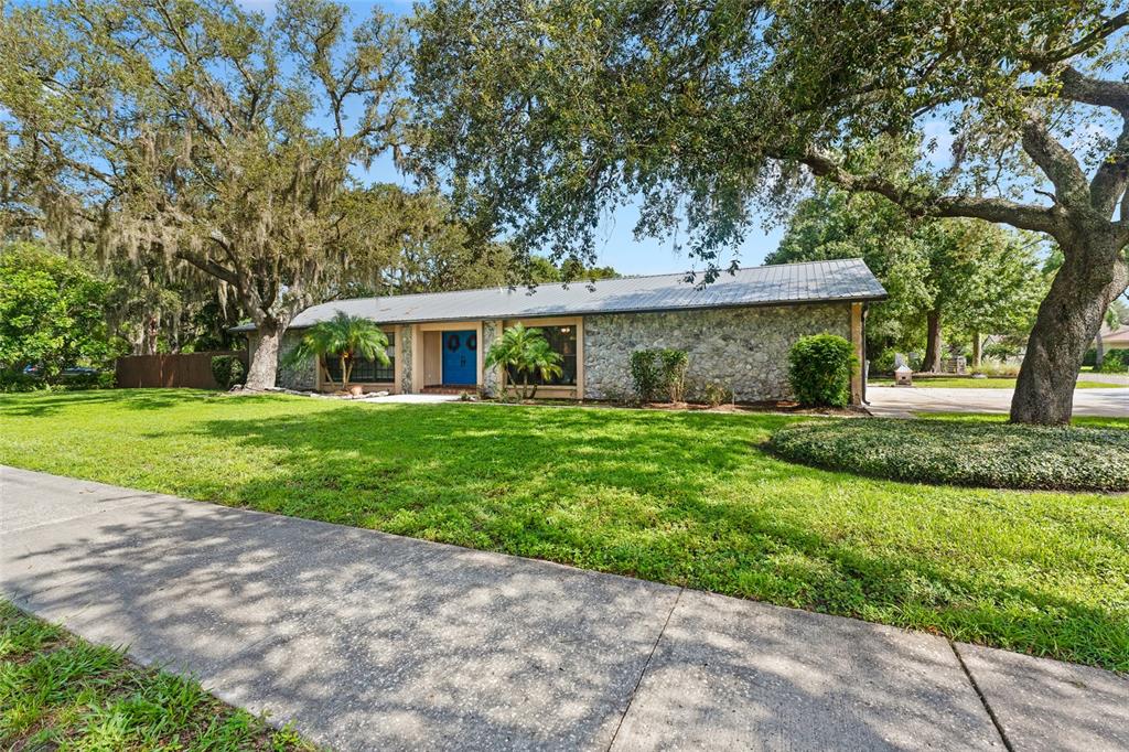 A single-story stone house with a metal roof and blue double front doors — 3011 LAKE ELLEN DRIVE, TAMPA, FL