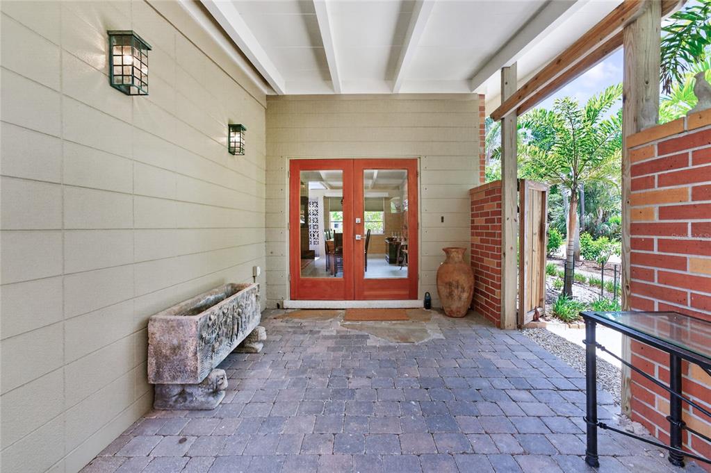 A covered patio features brick pavers, a stone planter, and double glass doors — 20 SPANIARDS ROAD, PLACIDA, FL