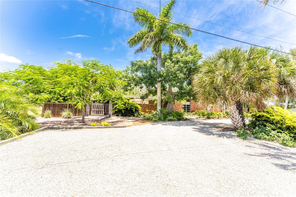 A gravel driveway leads to a single-story brick house surrounded by lush tropical trees — 20 SPANIARDS ROAD, PLACIDA, FL