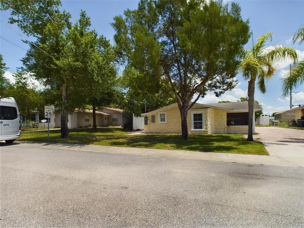 A yellow stone-faced house sits on a grassy lot next to a palm tree — 617 LIME, AUBURNDALE, FL