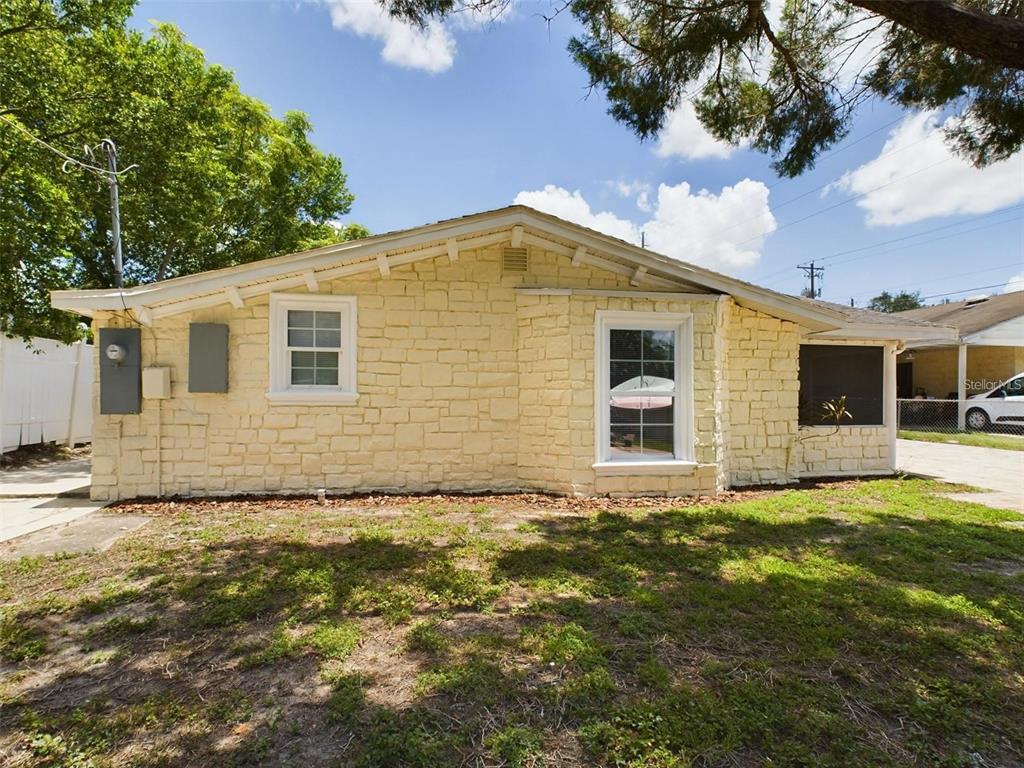 The exterior of a single-story house features light yellow stone siding and two windows — 617 LIME, AUBURNDALE, FL