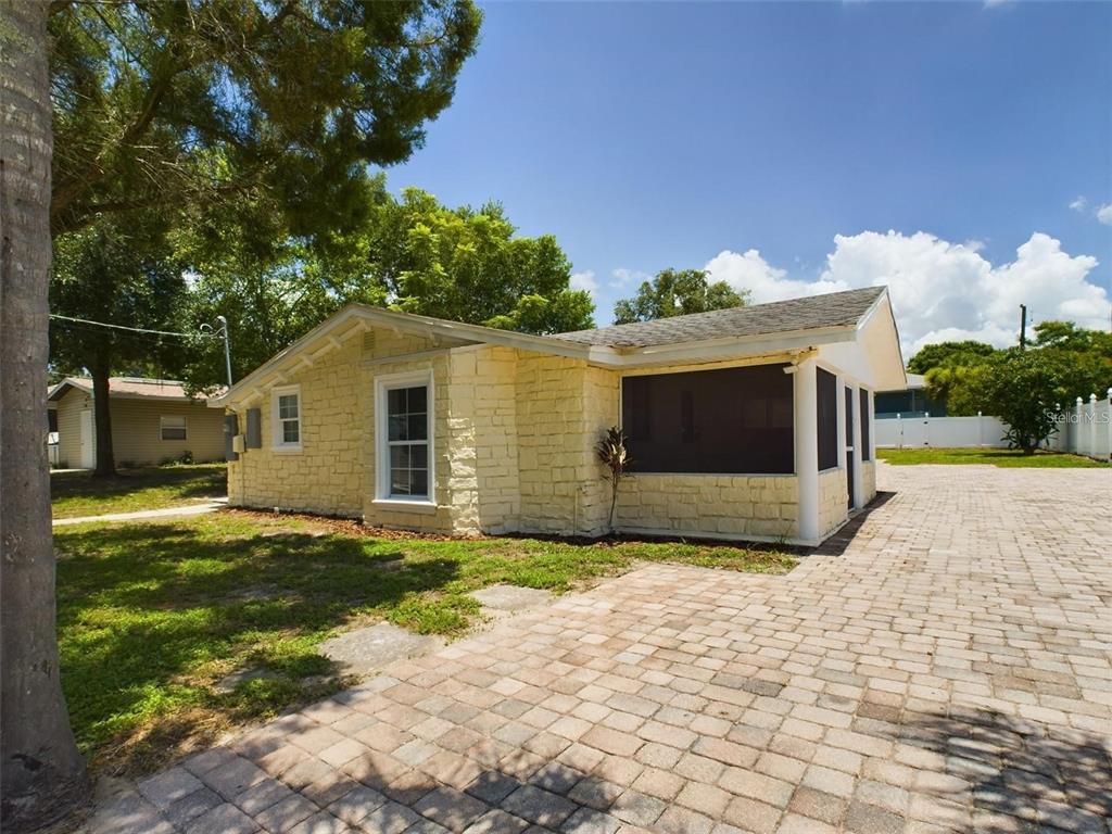 A yellow stone-faced house features a screened-in porch and a large brick paver driveway — 617 LIME, AUBURNDALE, FL