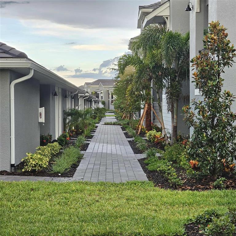 A paved walkway leads between two gray residential buildings lined with palm trees and landscaping — 17470 OPAL SAND DRIVE UNIT 201, VENICE, FL