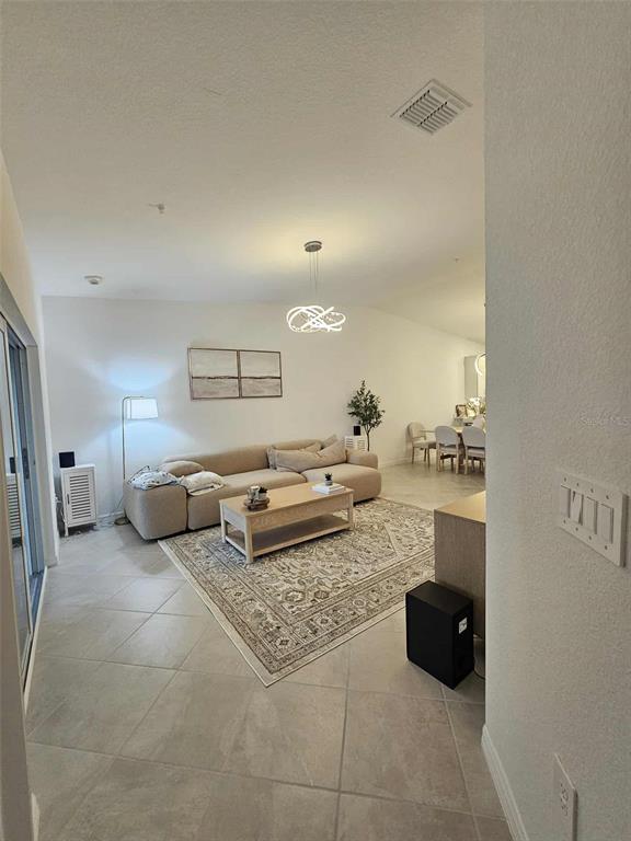 A living room with tile flooring, a beige sectional sofa, and a patterned area rug — 17470 OPAL SAND DRIVE UNIT 201, VENICE, FL