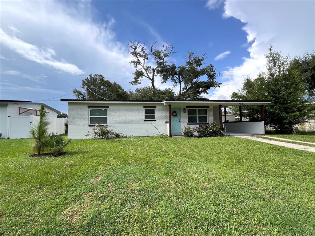 A single-story white brick house features a light blue front door and a carport — 2004 E BROAD STREET, TAMPA, FL