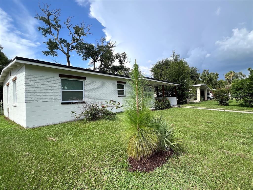 A white, single-story brick house with a front porch sits on a grassy lawn — 2004 E BROAD STREET, TAMPA, FL