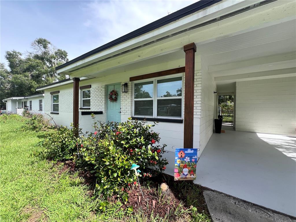 A white brick house exterior features a light blue front door and a covered carport — 2004 E BROAD STREET, TAMPA, FL