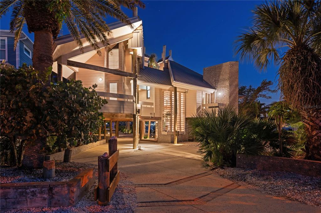 A stilt house with a concrete driveway and palm trees at twilight — 151 PUNTA VISTA DRIVE, ST PETE BEACH, FL