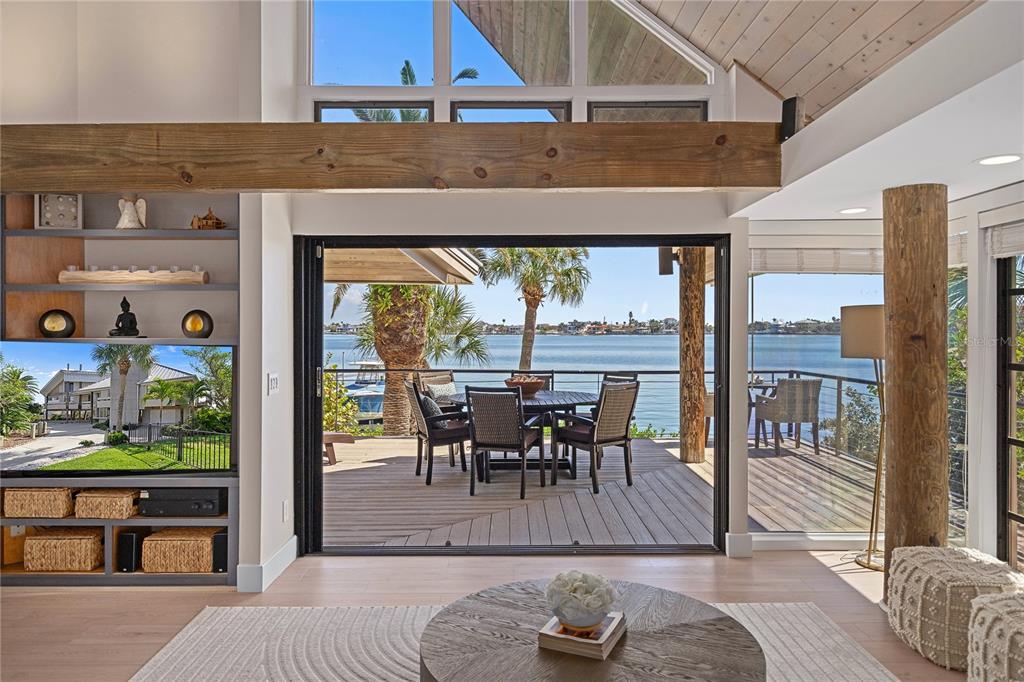 A living room with a wooden beam, built-in shelves, and sliding doors opening to a deck — 151 PUNTA VISTA DRIVE, ST PETE BEACH, FL