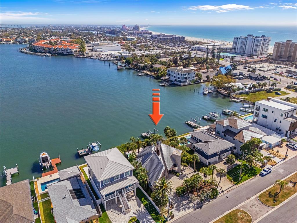 An aerial view shows waterfront houses with private docks along a bay near the beach — 151 PUNTA VISTA DRIVE, ST PETE BEACH, FL