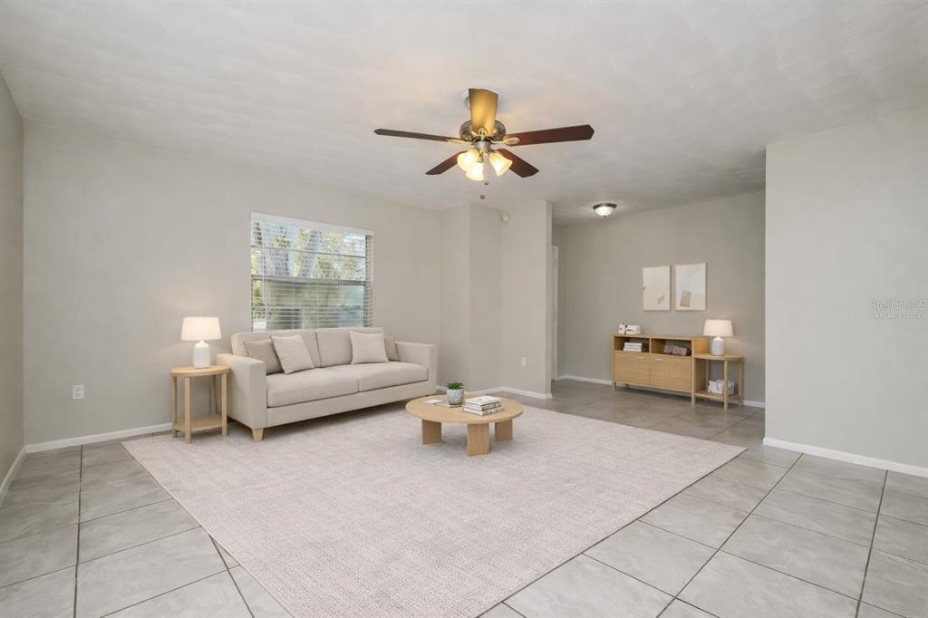 This living room features light-colored tile flooring, a beige sofa, and a central ceiling fan — 505 E MORGAN STREET, TARPON SPRINGS, FL