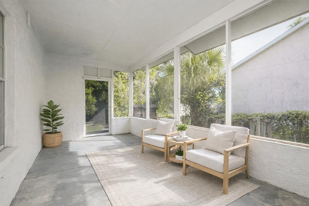 A screened-in porch with concrete floors, two armchairs, a side table, and a potted plant — 505 E MORGAN STREET, TARPON SPRINGS, FL