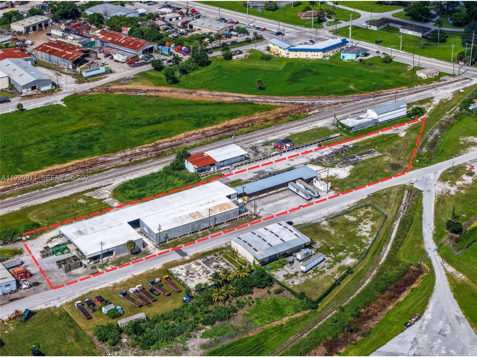 An aerial view shows industrial warehouse buildings and a rail line outlined in red — 901 NW 9th St, Belle Glade FL 33430, BELLE GLADE, FL