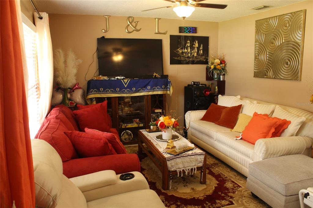 A living room features a red sofa, a white sofa, and a central coffee table — 5705 SE 2ND STREET, OCALA, FL