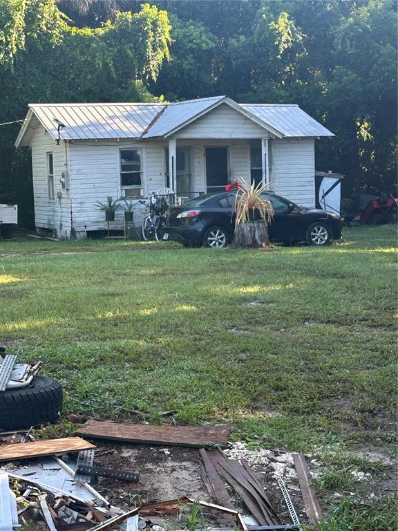 A white, single-story house with a metal roof sits behind a black car and debris — 2660 S US HIGHWAY 17, CRESCENT CITY, FL
