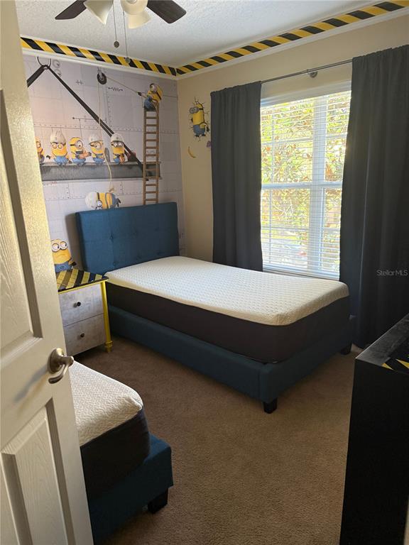 A bedroom features a blue bed, a matching nightstand, and Minion-themed wallpaper and decor — 860 ASSEMBLY COURT, REUNION, FL
