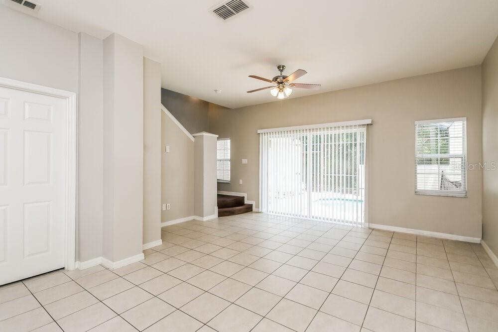 A living room with light tile flooring, a ceiling fan, and sliding glass patio doors — 4502 ALBERTO CIRCLE, KISSIMMEE, FL