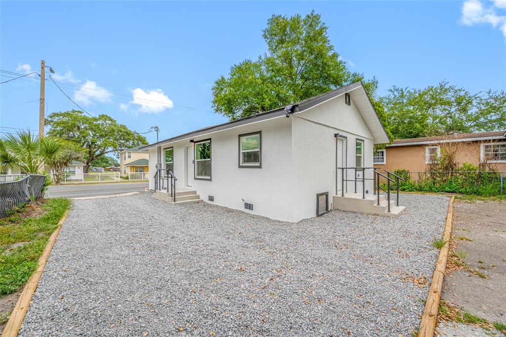 A white stucco house with a gravel driveway and two separate exterior entryways — 308 W 10TH STREET, LAKELAND, FL