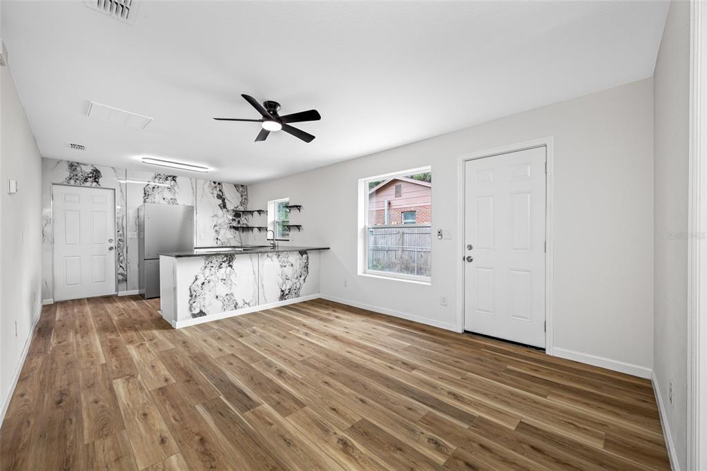 A kitchen and living area featuring wood-look flooring, white walls, and a marble-patterned island — 308 W 10TH STREET, LAKELAND, FL