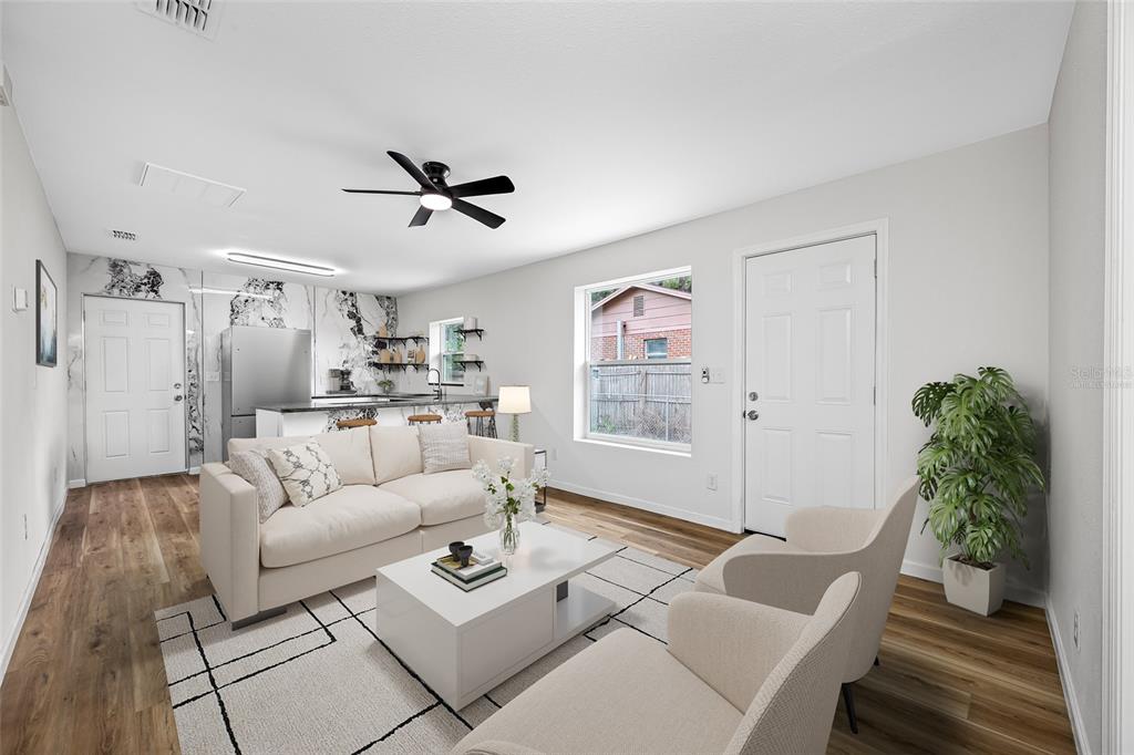 A living room with a white sofa, two armchairs, and an open kitchen with marble-patterned walls — 308 W 10TH STREET, LAKELAND, FL