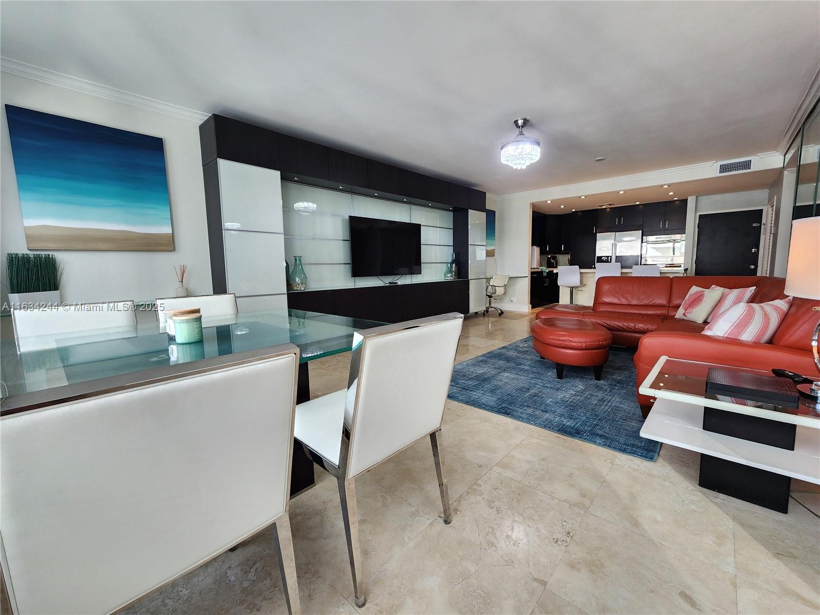 An open-concept living and dining area features a glass table, red sofa, and media wall — 3505 S Ocean Dr # 1409, Hollywood FL 33019, HOLLYWOOD, FL
