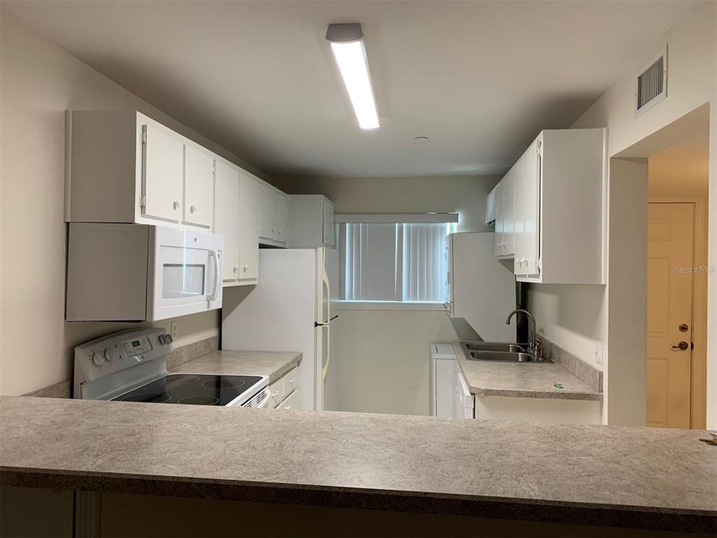 A kitchen features white cabinets, a white refrigerator, a stove, and a laminate countertop — 150 HARBORSIDE AVENUE UNIT 229, PUNTA GORDA, FL