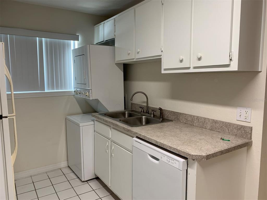 A kitchen features white cabinets, a double sink, a dishwasher, and a stacked laundry unit — 150 HARBORSIDE AVENUE UNIT 229, PUNTA GORDA, FL