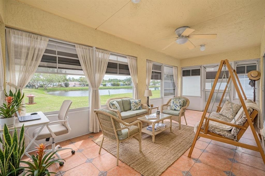 A sunroom with tile floors, wicker furniture, a hanging swing, and views of a pond — 57 HUARTE WAY, PORT ST LUCIE, FL