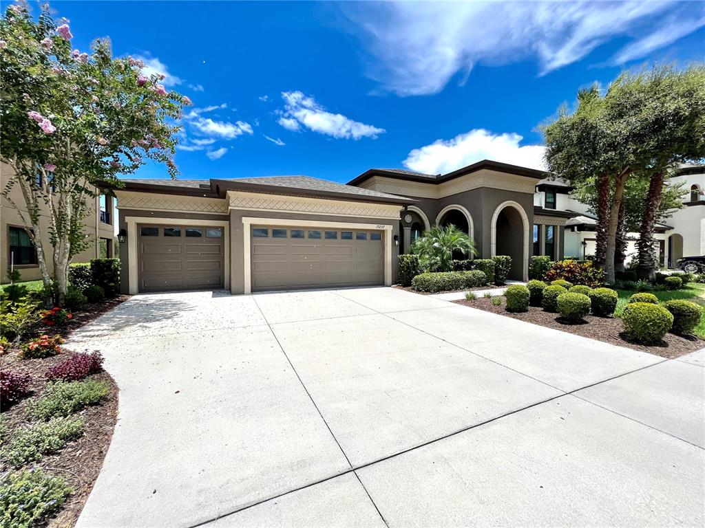 A single-story house with a three-car garage, arched entryway, and landscaped front yard — 19237 FALCON CREST BOULEVARD, LAND O LAKES, FL