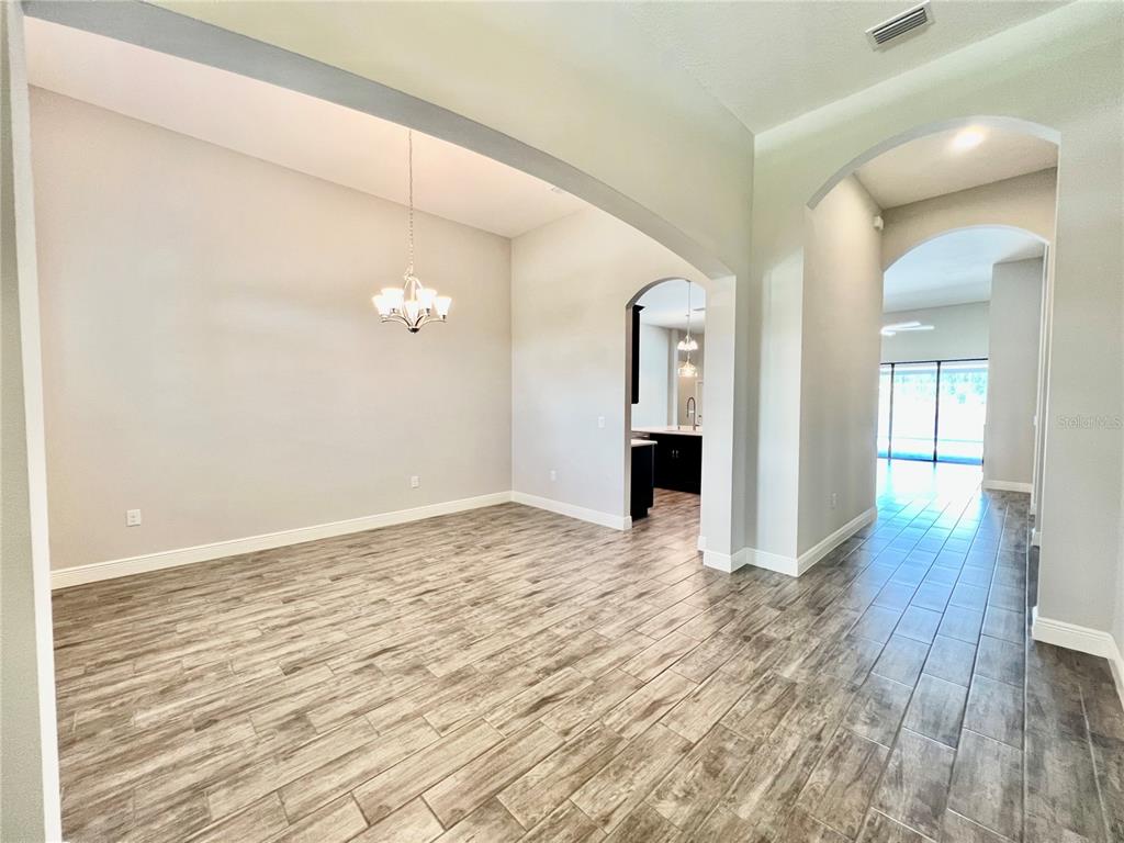 An empty dining room with wood-look tile flooring, a chandelier, and arched entryways — 19237 FALCON CREST BOULEVARD, LAND O LAKES, FL