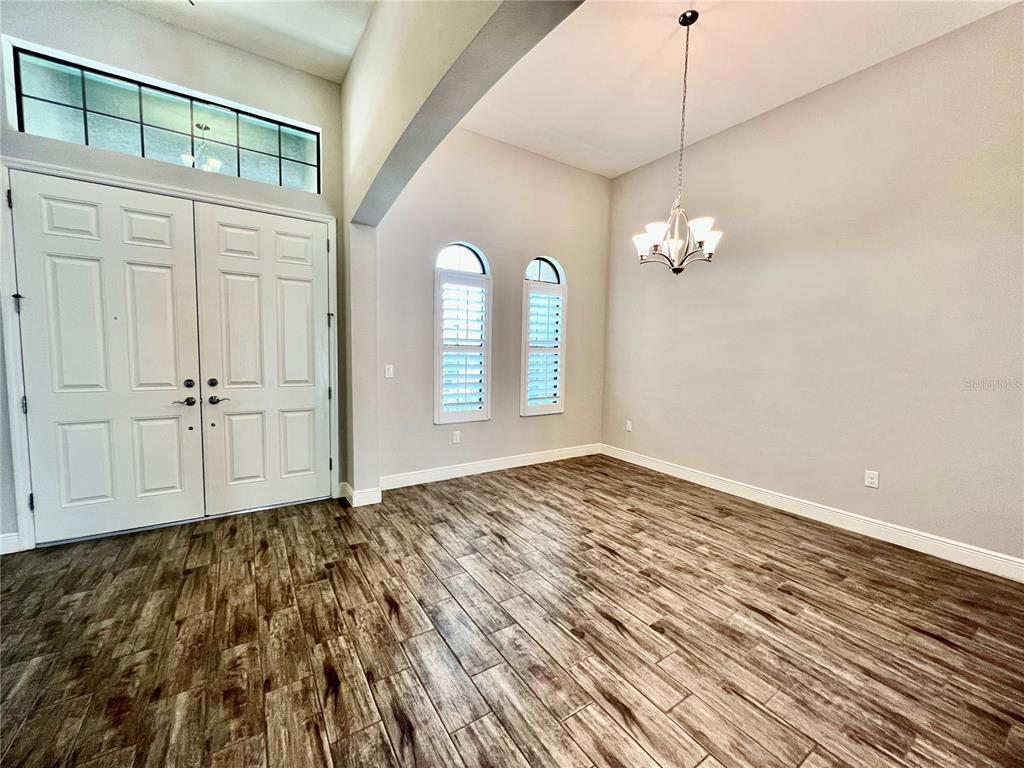 An entryway features double doors, wood-look tile flooring, arched windows, and a hanging chandelier — 19237 FALCON CREST BOULEVARD, LAND O LAKES, FL
