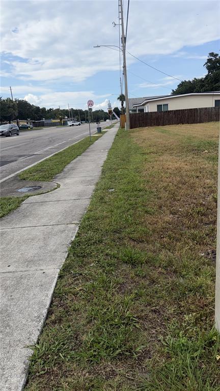 A sidewalk runs alongside a grassy lot next to a road with a wooden fence — 4341 LENOX BOULEVARD, ORLANDO, FL