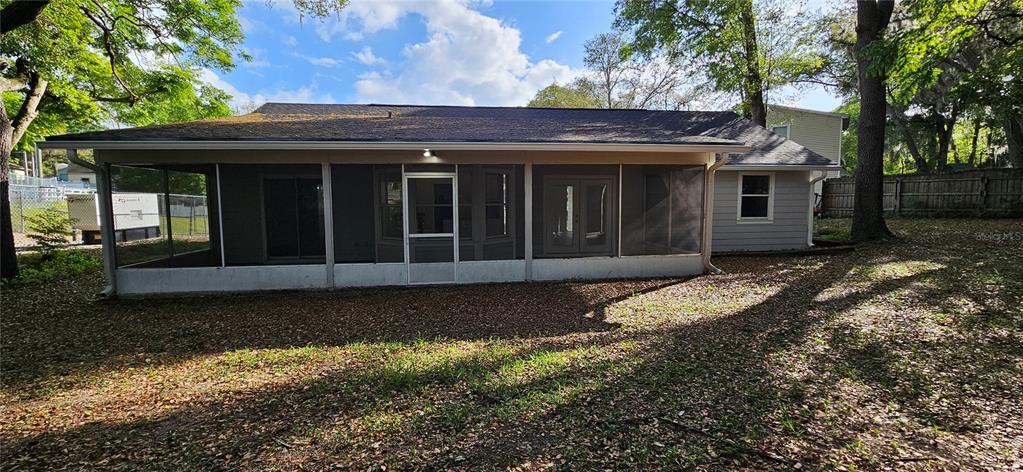 The rear exterior of a house features a large screened-in porch and gray siding — 370 S COBBLE COURT, MOUNT DORA, FL