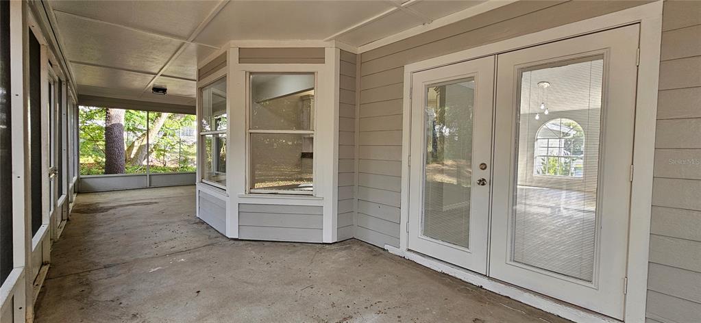 A covered concrete patio features a bay window and double glass doors — 370 S COBBLE COURT, MOUNT DORA, FL